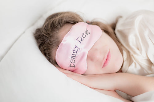 Woman sleeping with pink eye mask wording “beauty rest”